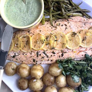 baked side of salmon on a plate with samphire and new potatoes.