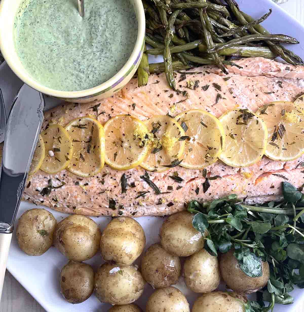 baked side of salmon on a plate with samphire and new potatoes.