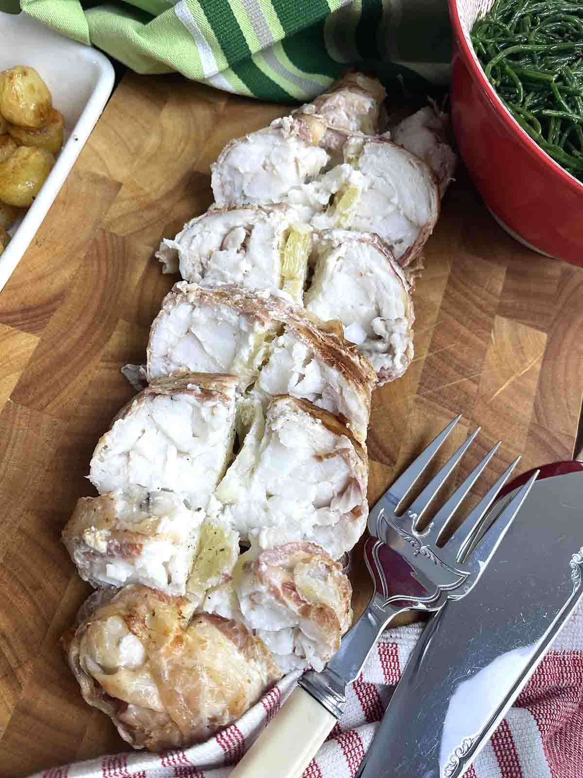baked monkfish tails sliced on a board.