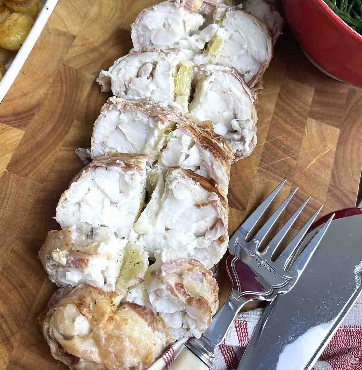 baked monkfish tails sliced on a board.