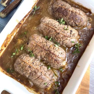 Beef olives in brown sauce in a serving dish.