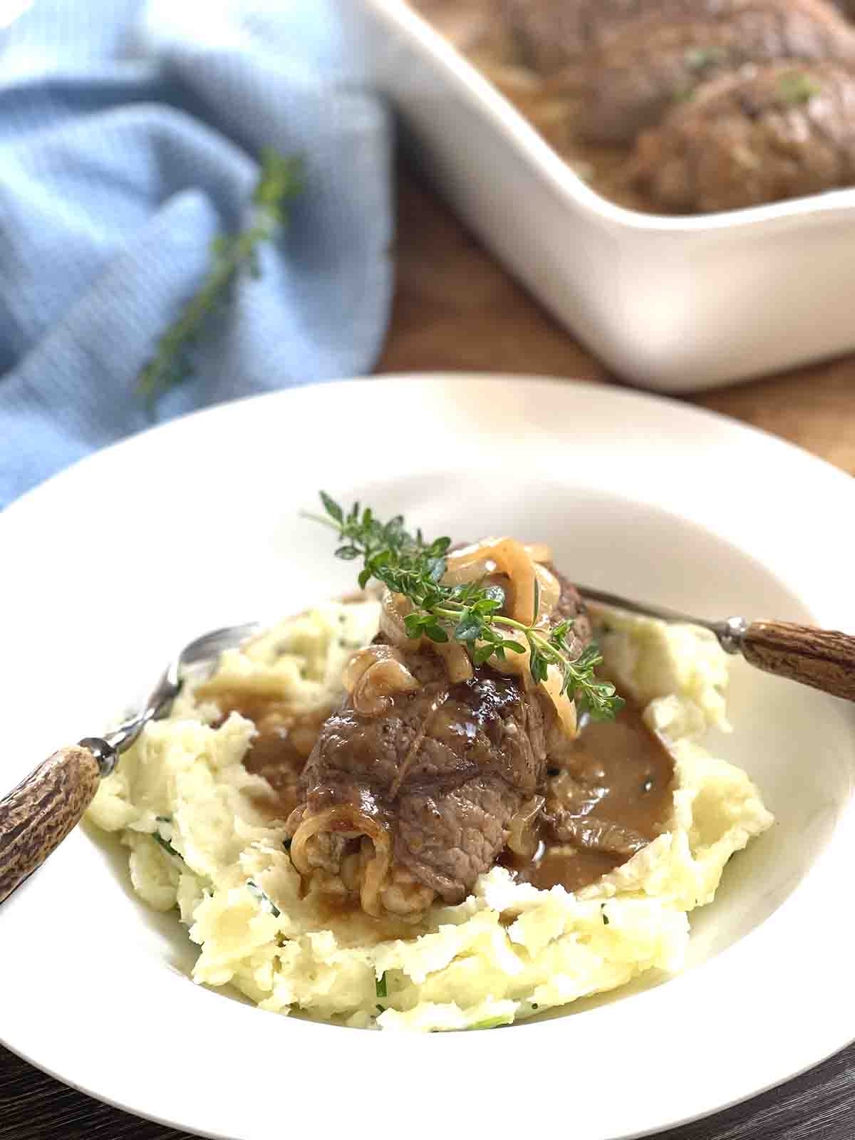 beef roll on a bed of mashed potato with sauce.