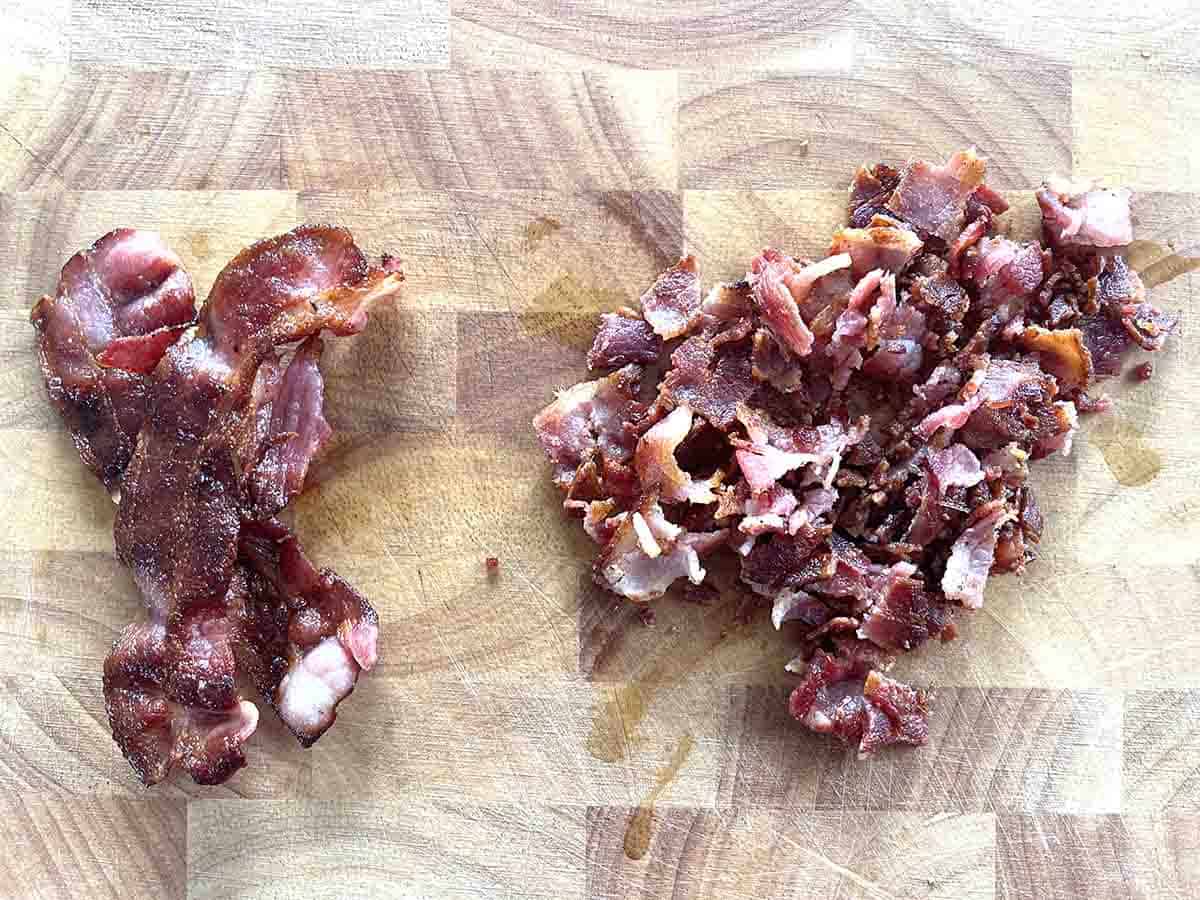 cooked bacon, part chopped on a wooden board.