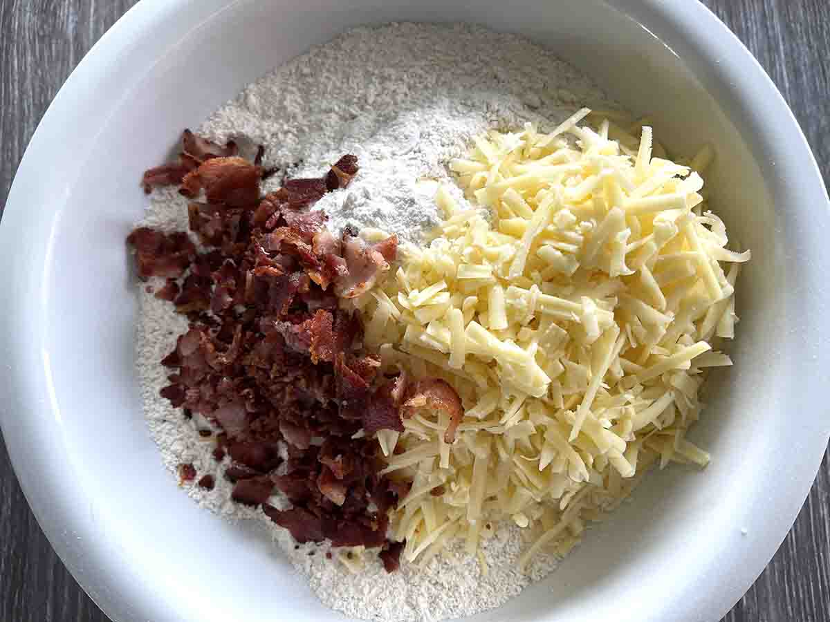 flour and butter mixture in a bowl with grated cheese and cooked chopped bacon on top.