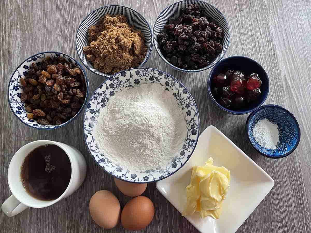 ingredients for tea loaf including raisins, cherries, sultanas, sugar, flour, eggs, butter, tea.