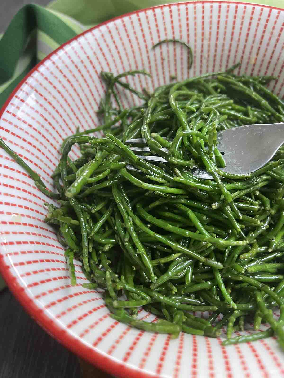 bowl of sea beans with a forkful held up.
