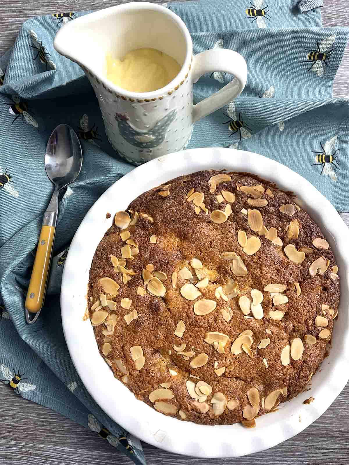Eve's pudding in a dish with custard in the background.