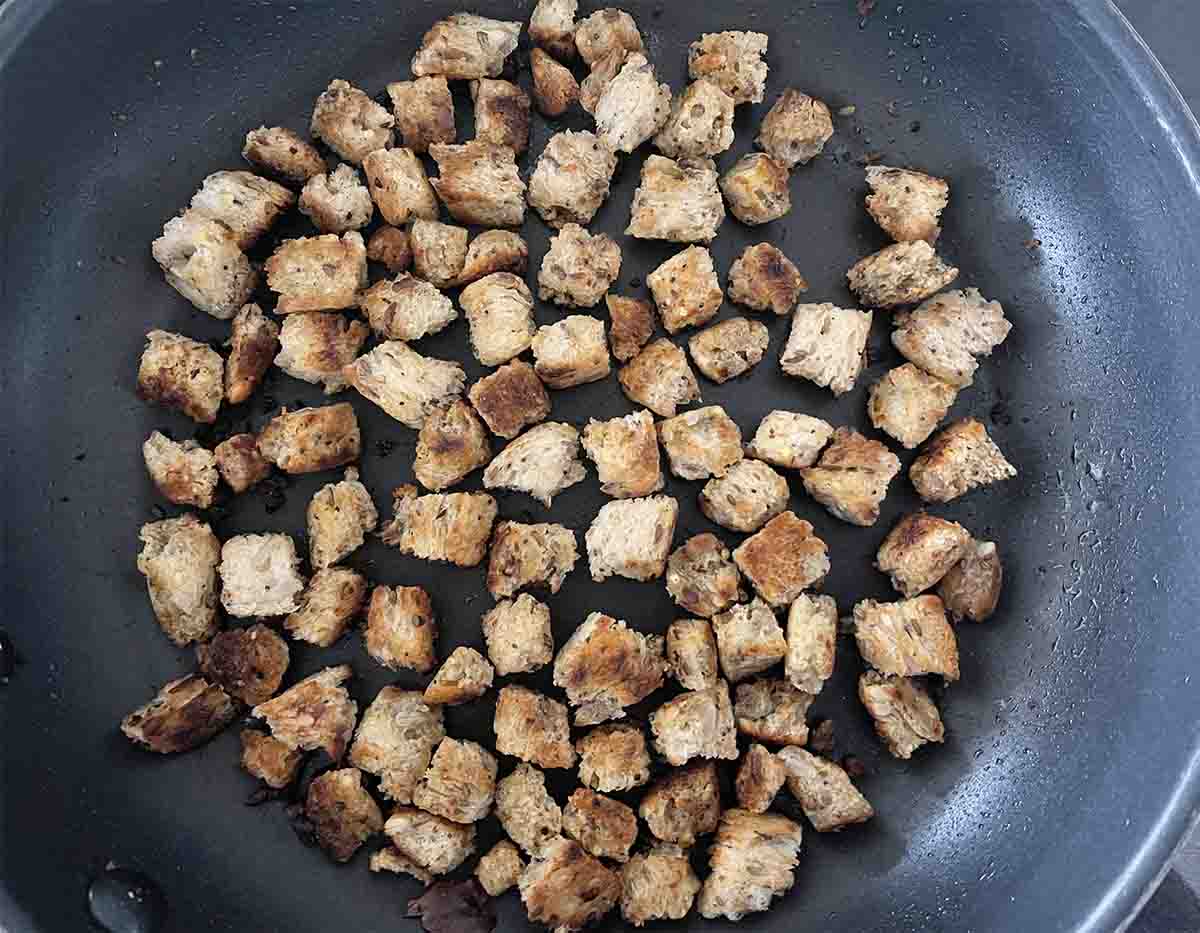 cubed bread frying in a pan.
