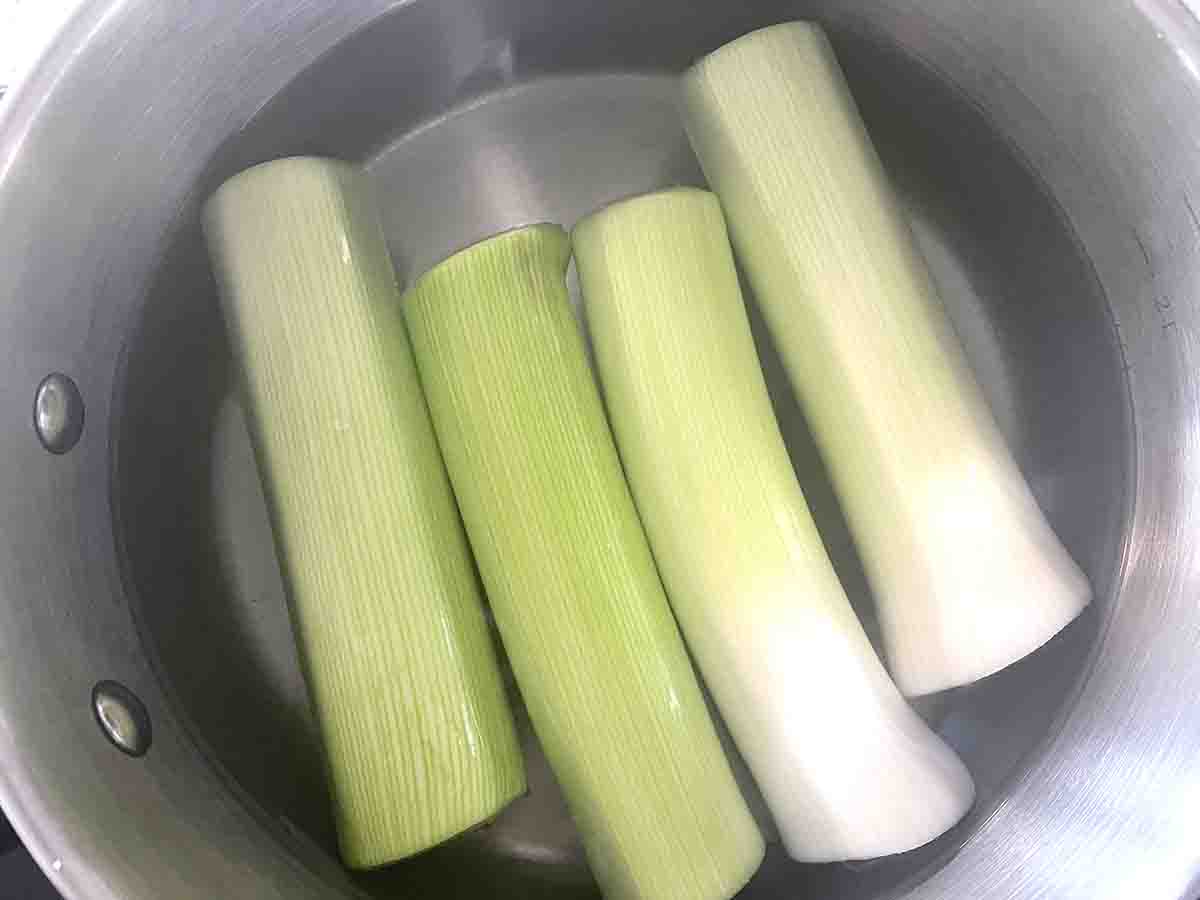 halved leeks in a saucepan of water.