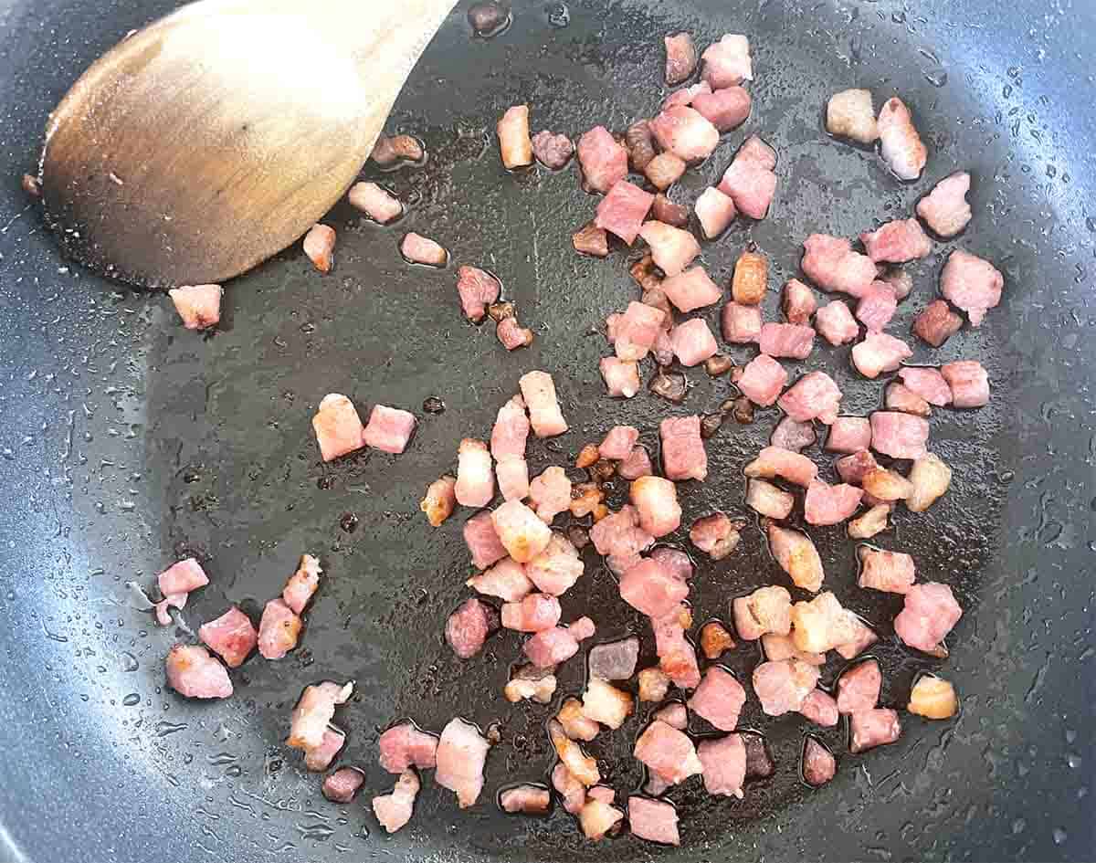 bacon lardons in a frying pan.