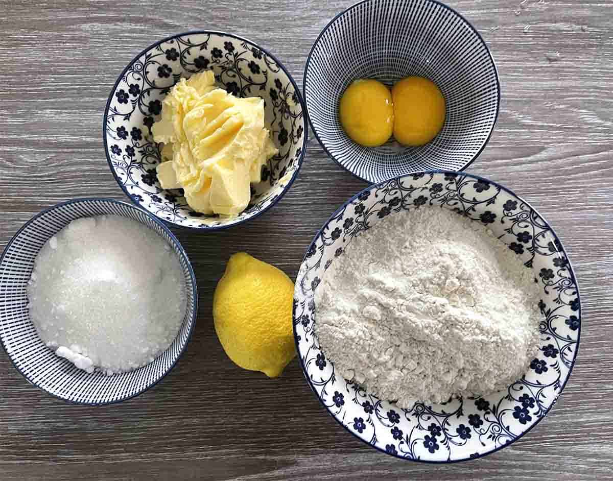 bowls of ingredients including eggs, sugar, butter, flower and lemon.
