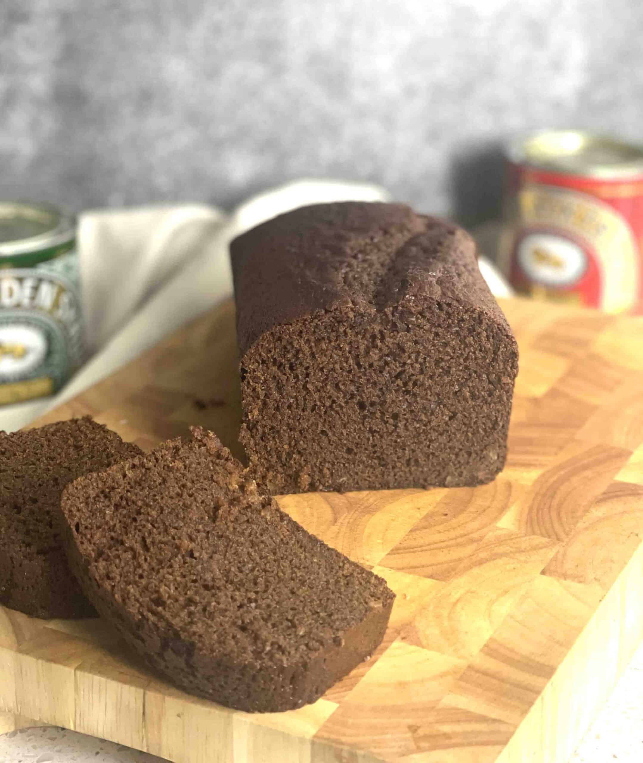 sliced ginger cake on a board with tin of syrup and treacle in the background.