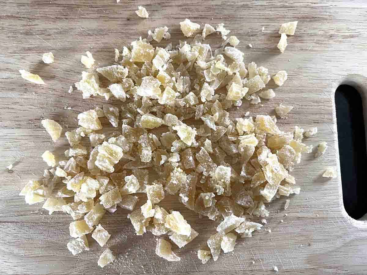 chopped crystalised ginger on a wooden board.