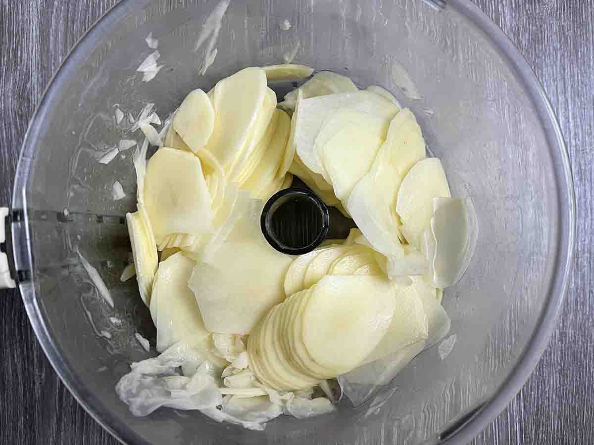 sliced potatoes in a food processor bowl.