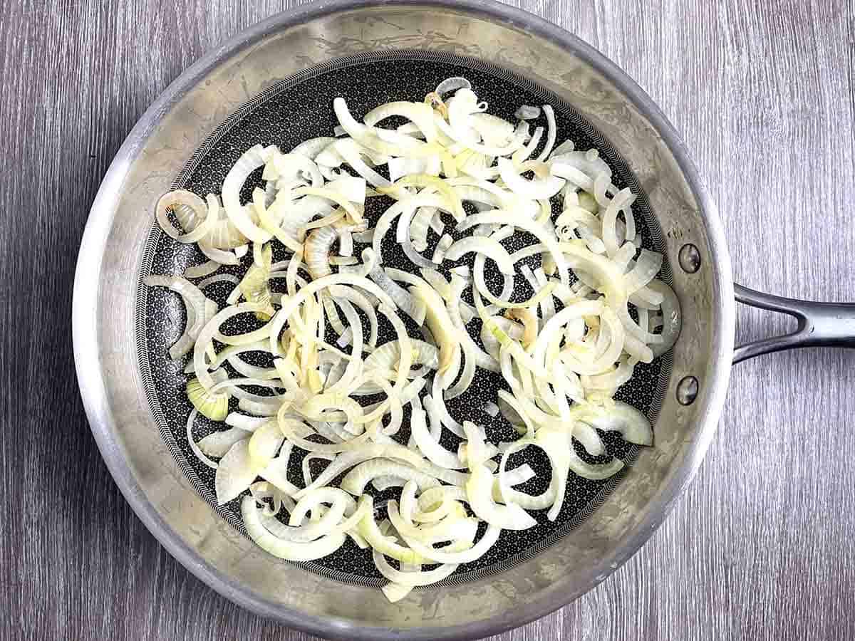 sliced onions frying in a pan.