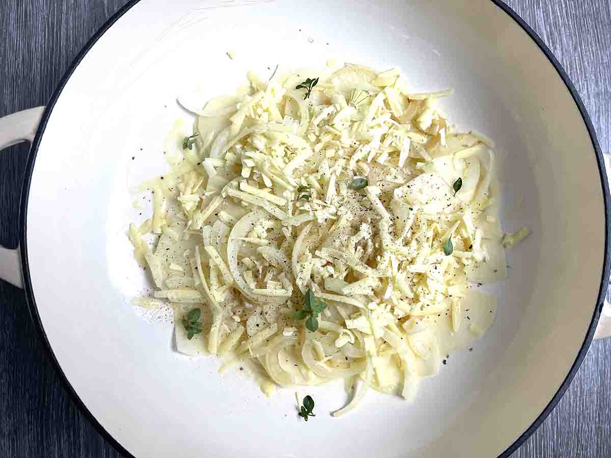 sliced potatoes and onions layered in a pan.