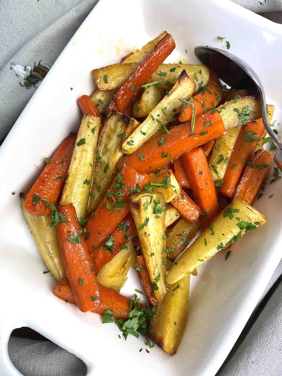 honey roasted carrots and parsnips in a white serving dish.
