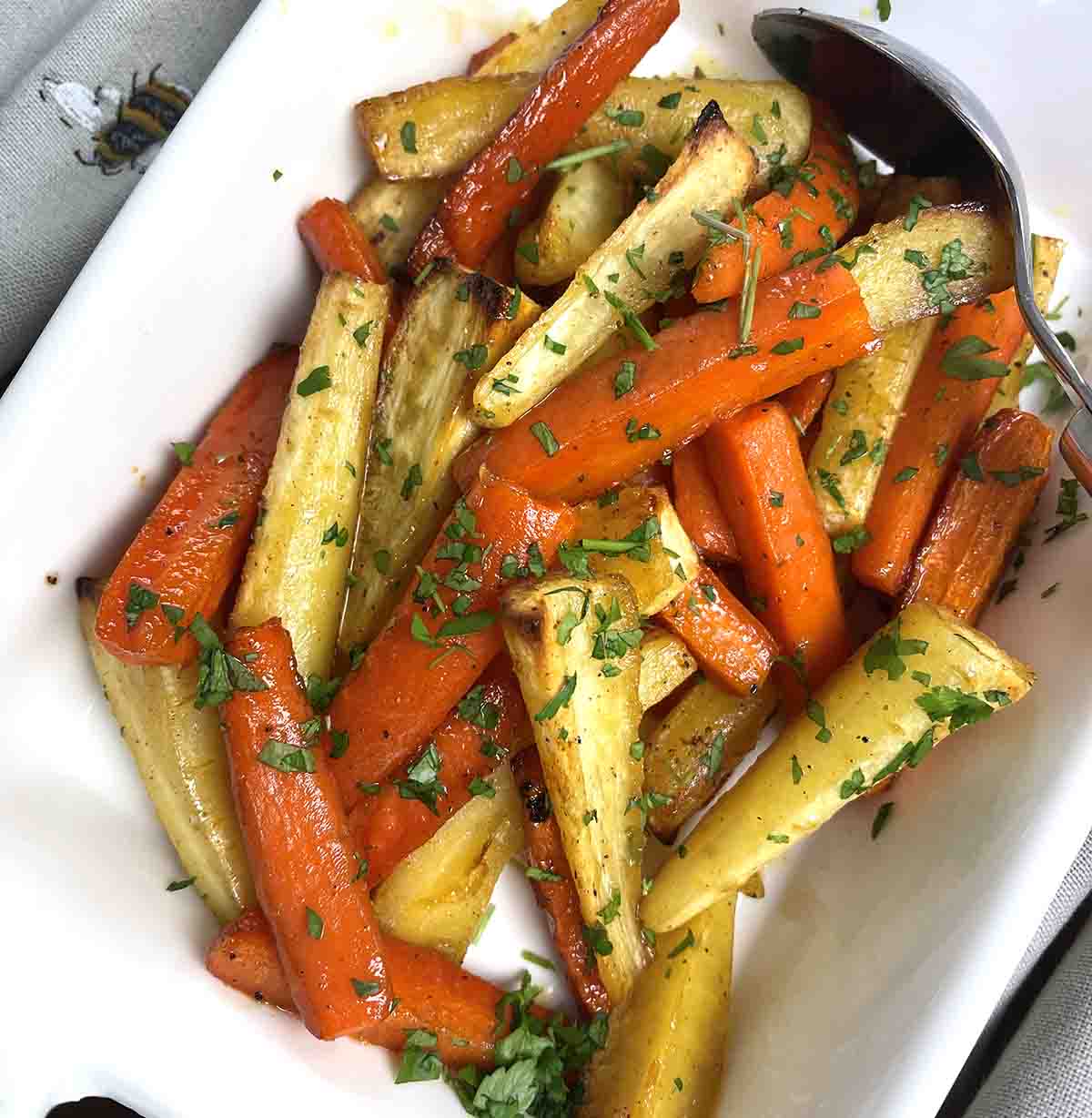 honey roasted carrots and parsnips in a white serving dish.
