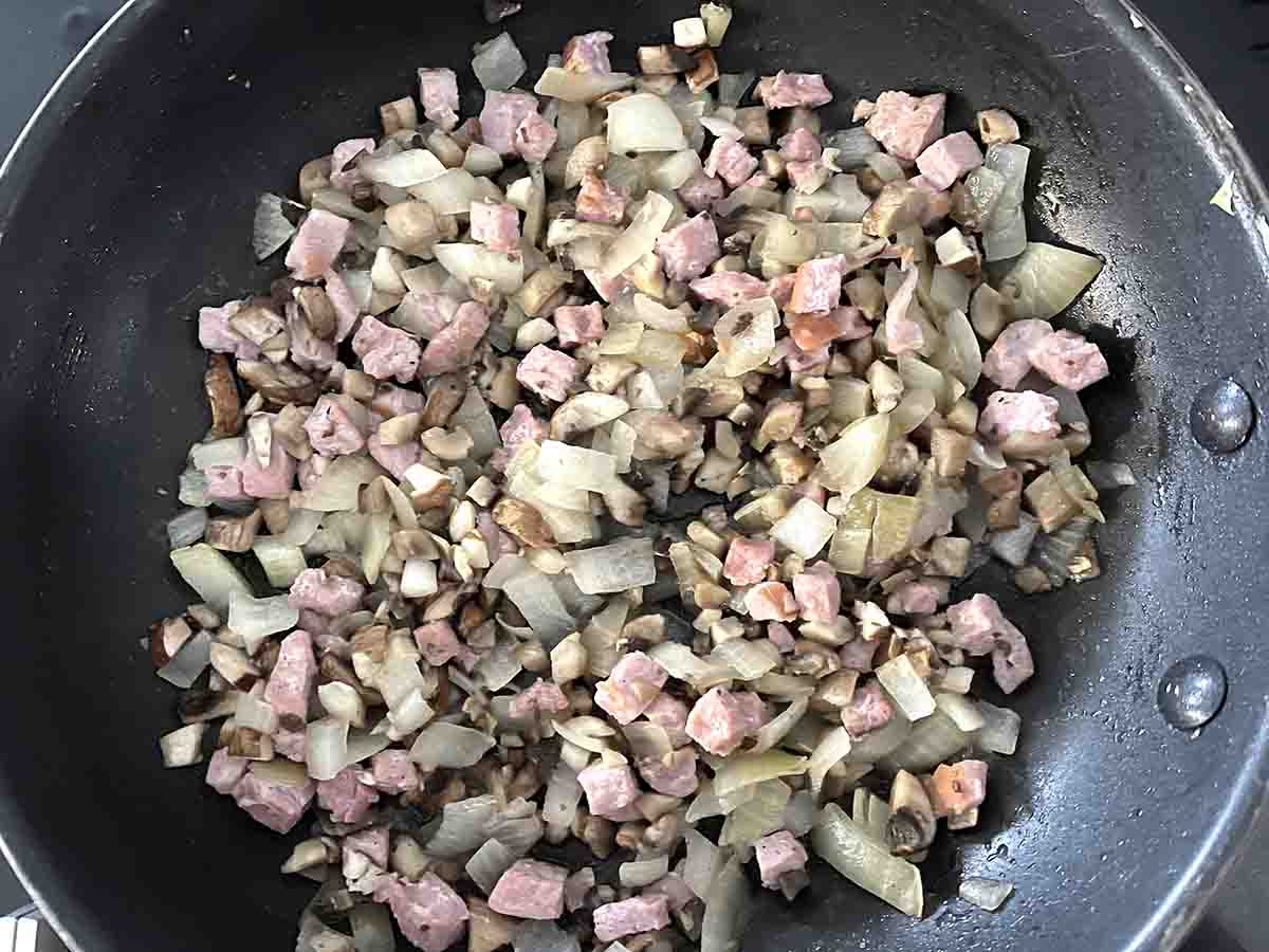 cooked muchrooms onions and bacon in a pan.