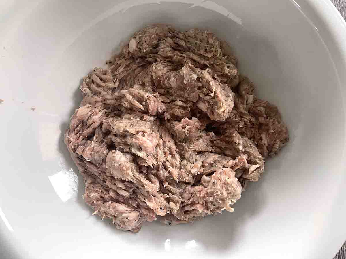 mashed sausages in a white bowl.
