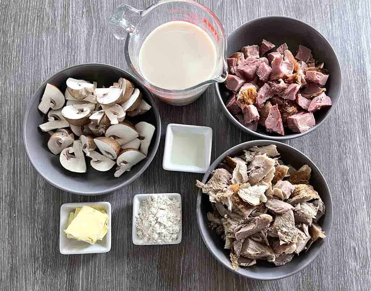 pie ingredients in bowls including mushrooms, ham, turkey butter, milk, stock, flour and seasoning.