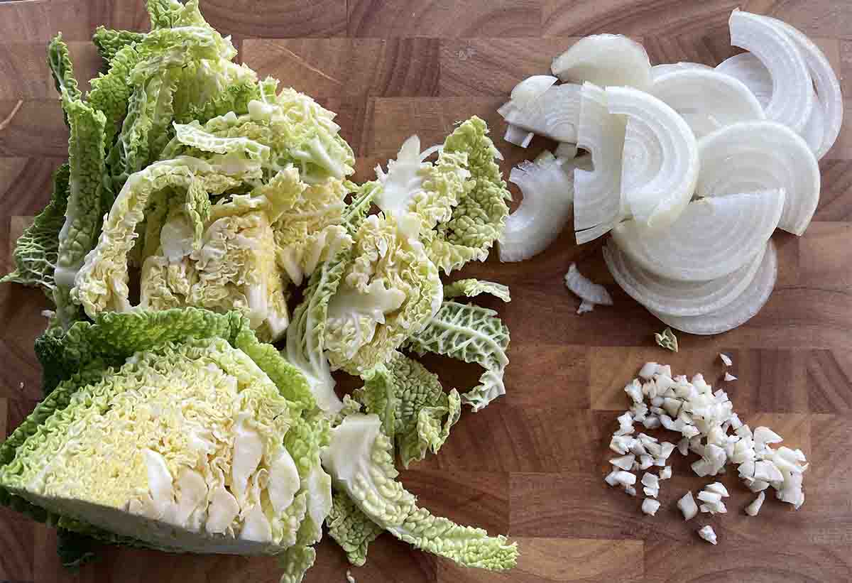 sliced cabbage and onions and chopped garlic on a board.