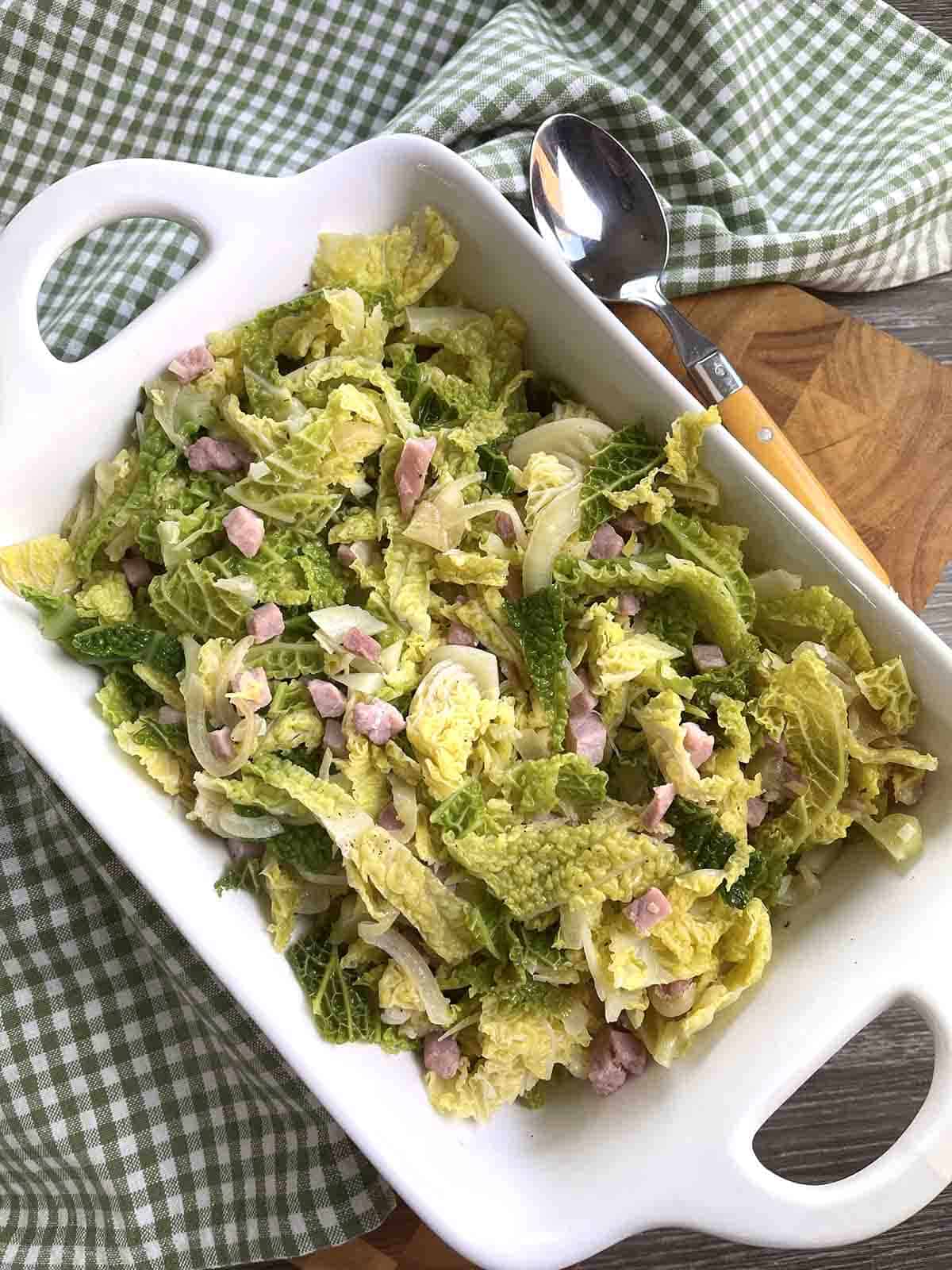 fried cabbage with bacon and onions in a serving dish.