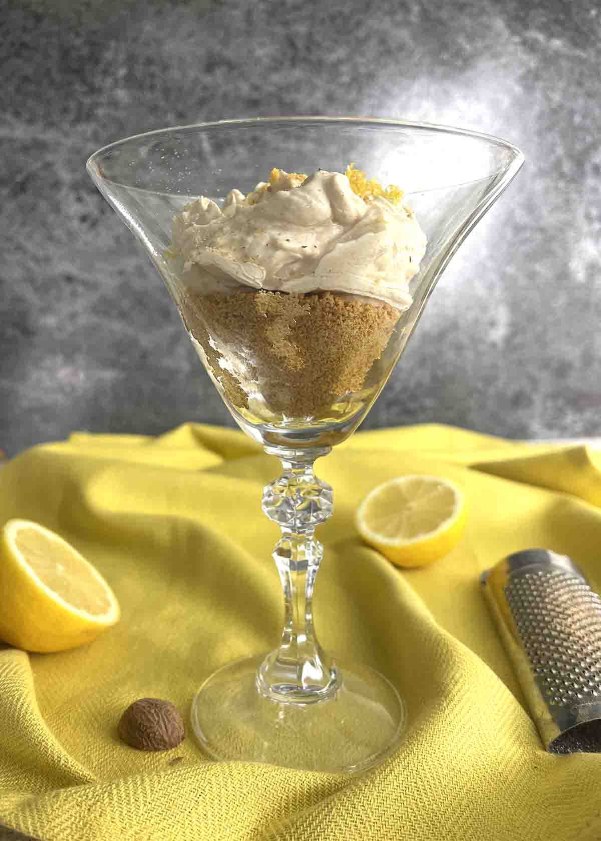 lemon syllabub in a glass with lemons.