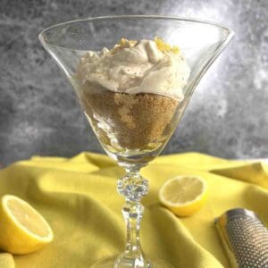 lemon syllabub in a glass with lemons.