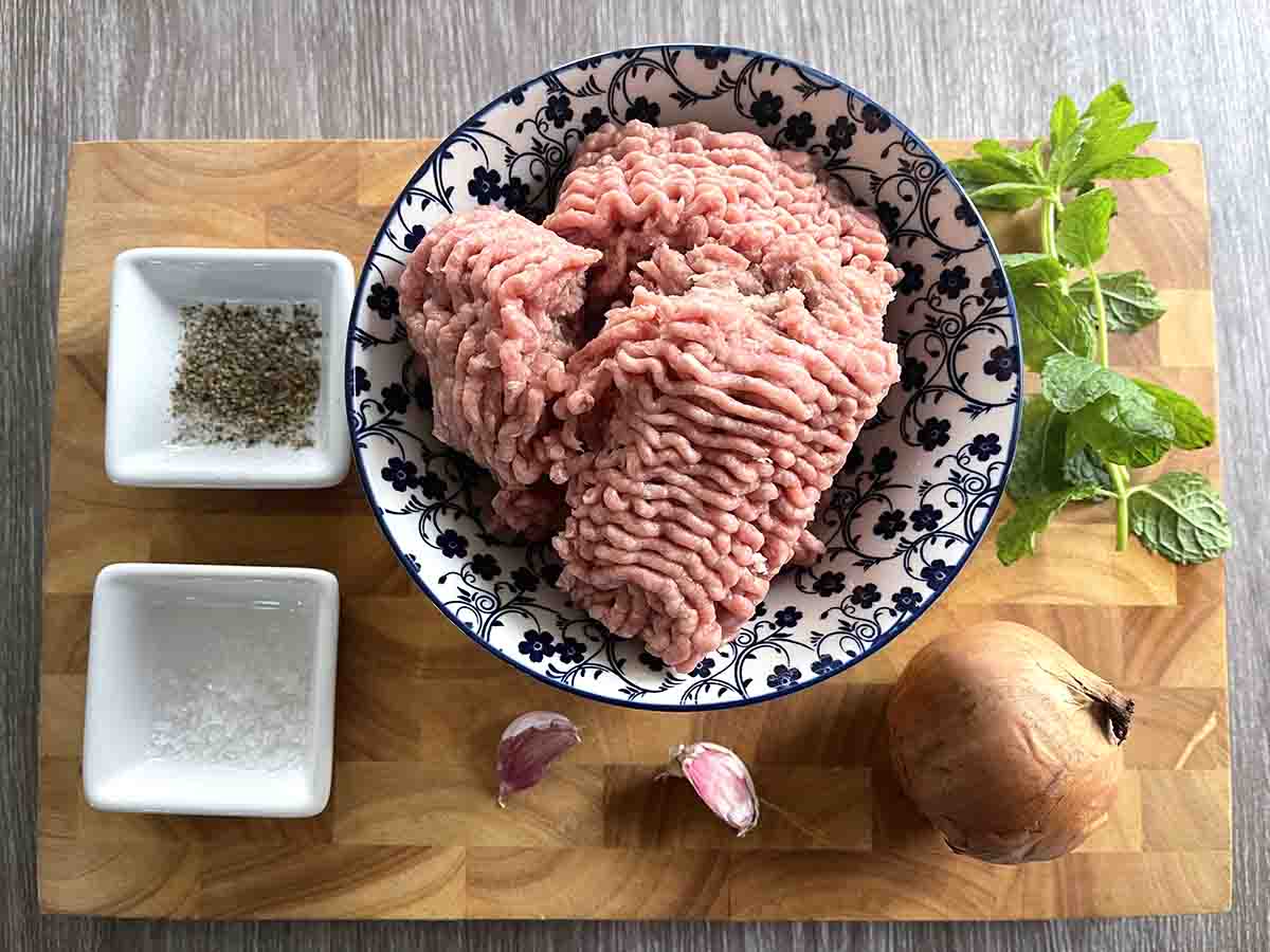 ingredients in bowls including lamb mince, onion, garlic, seasoning and mint.