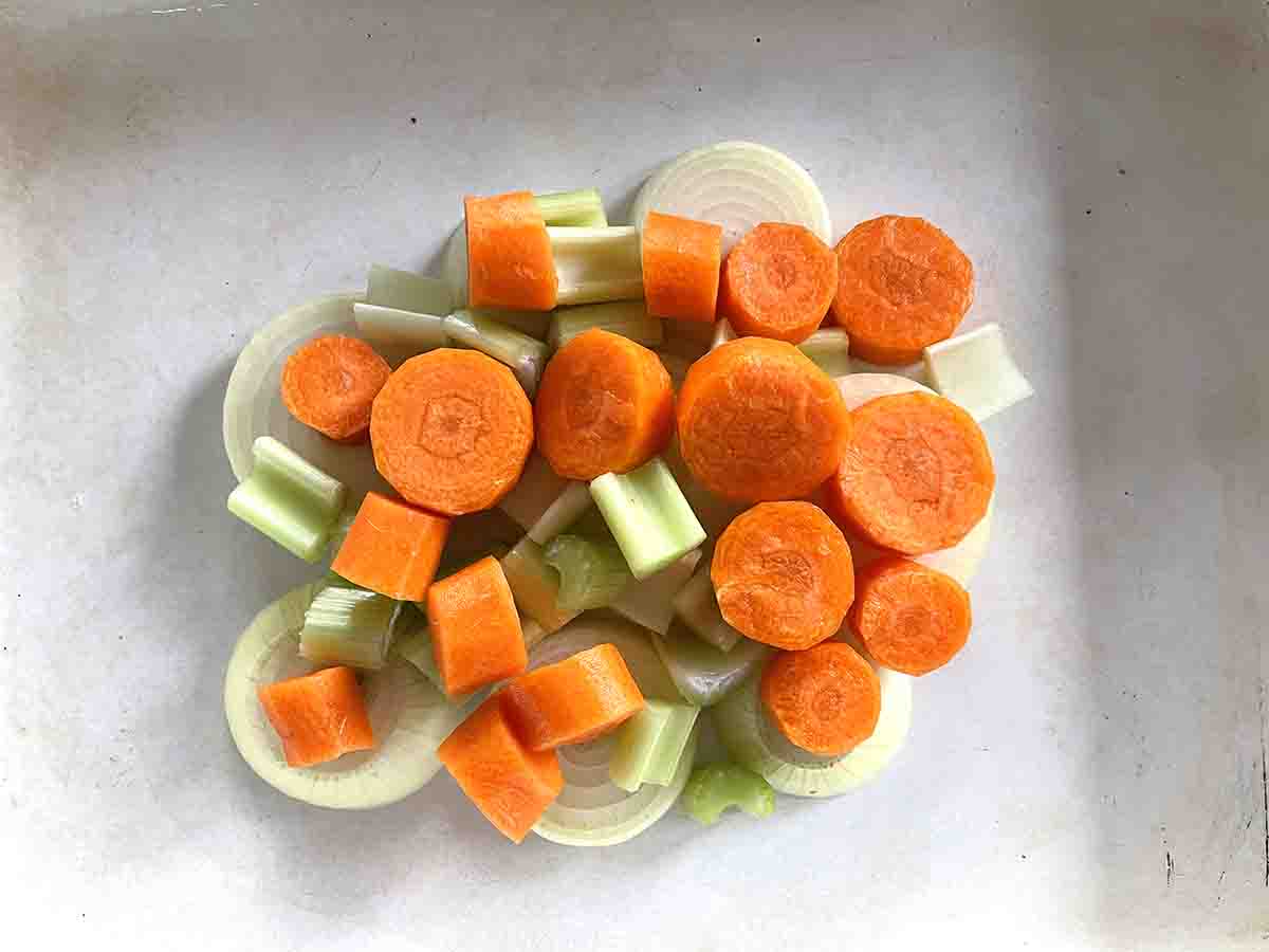 vut vegetables in a the base of a roasting dish.