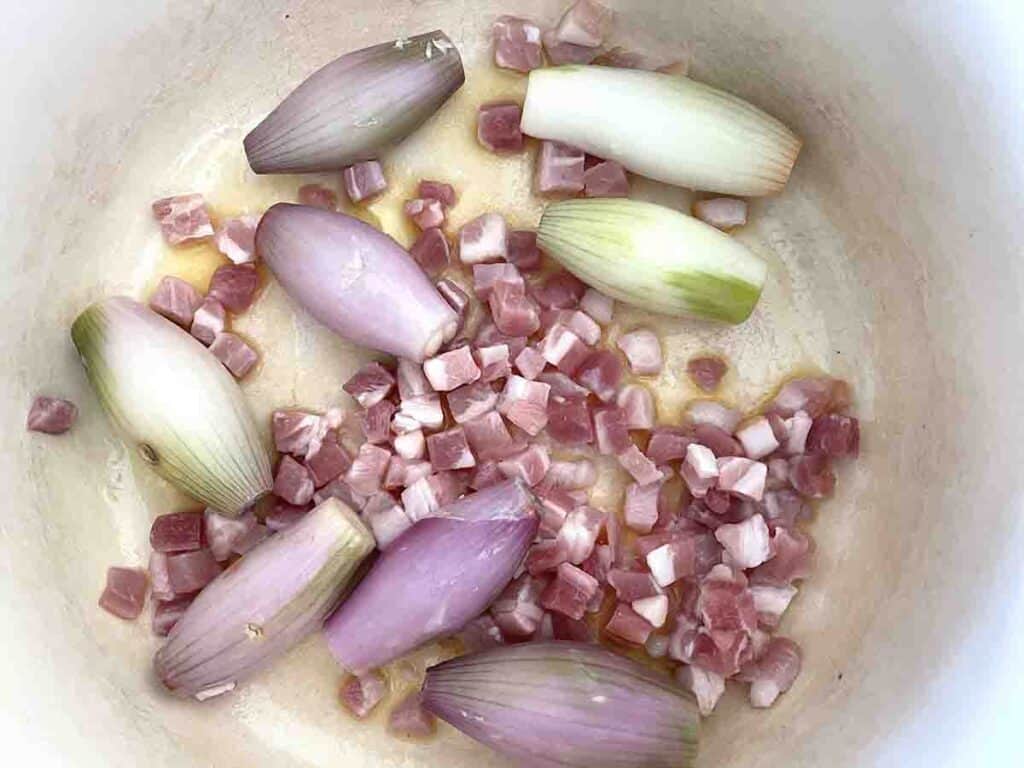 bacon and shallots in a pan.