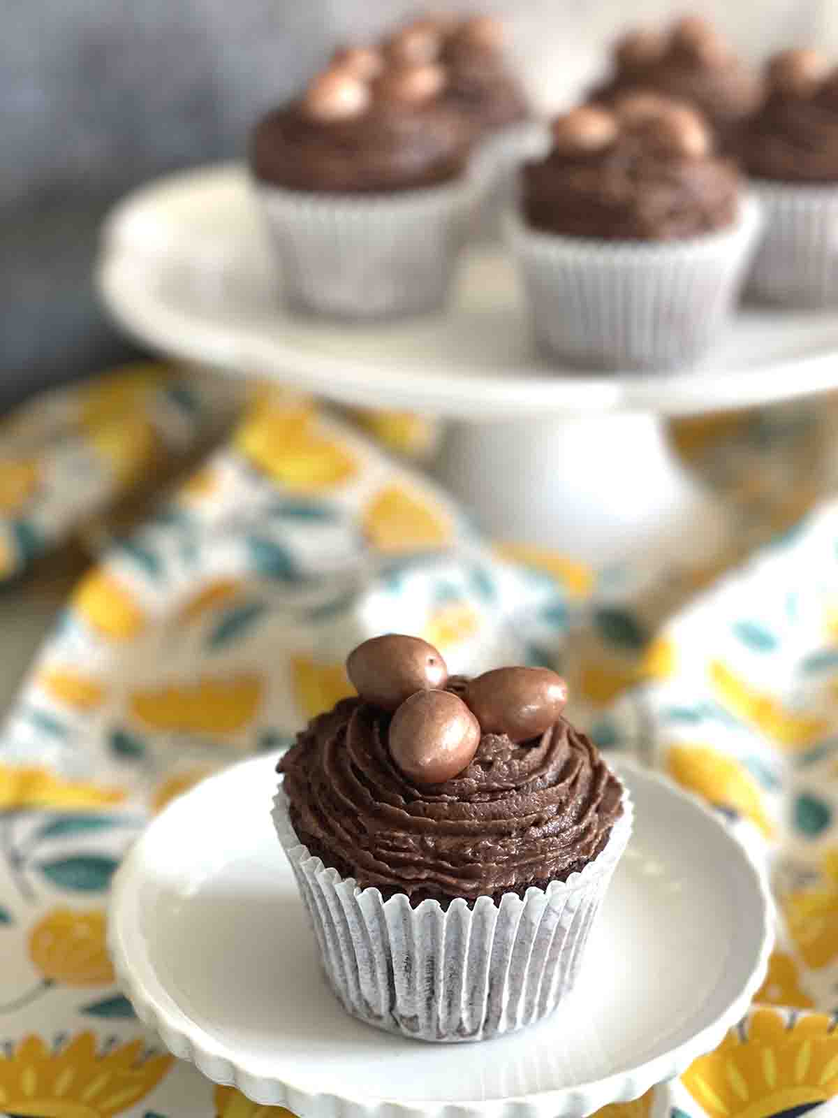 easter egg cupcakes on a display standard and one on a plate.