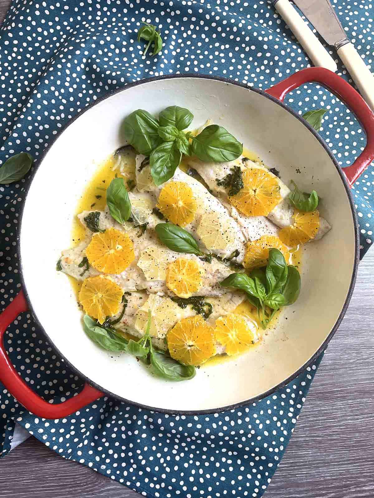 pan seared seabass with orange in a round pan.