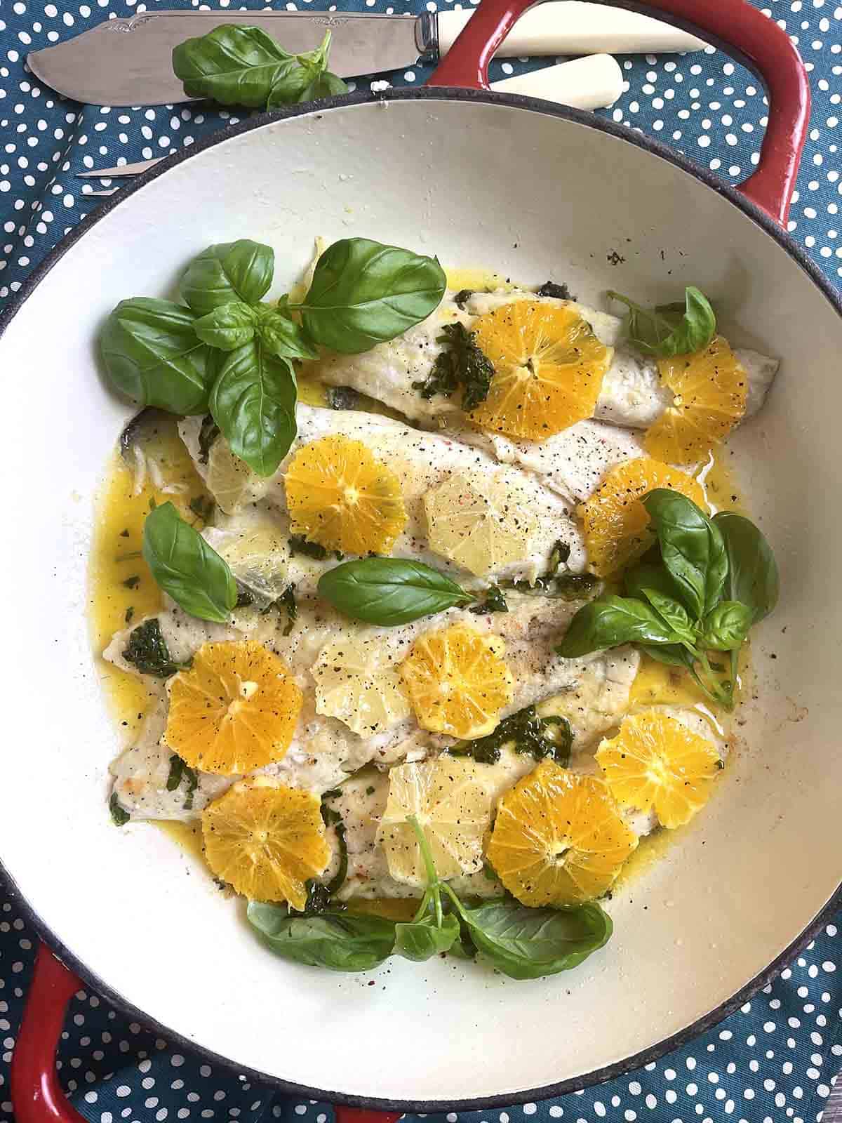close up of pan fried sea bass with citrus in a pan.