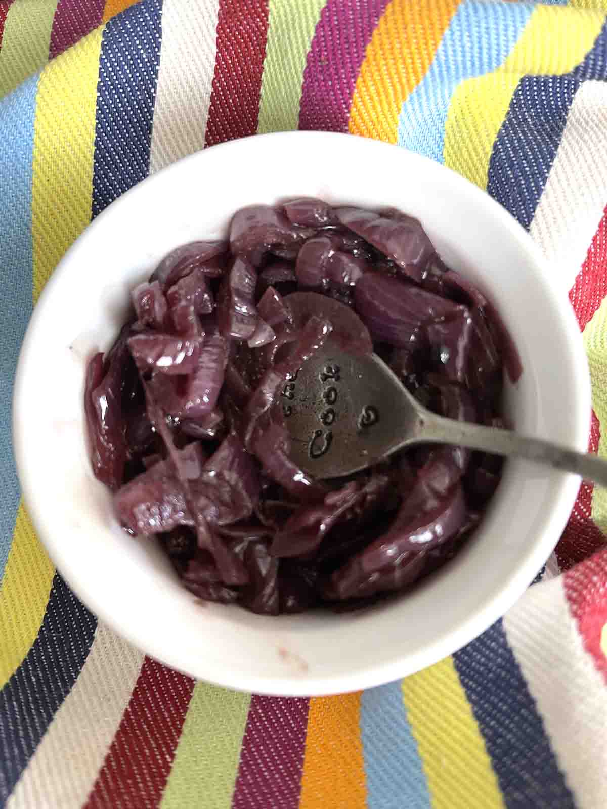 caramelised red onion chutney in a small pot with a spoon.