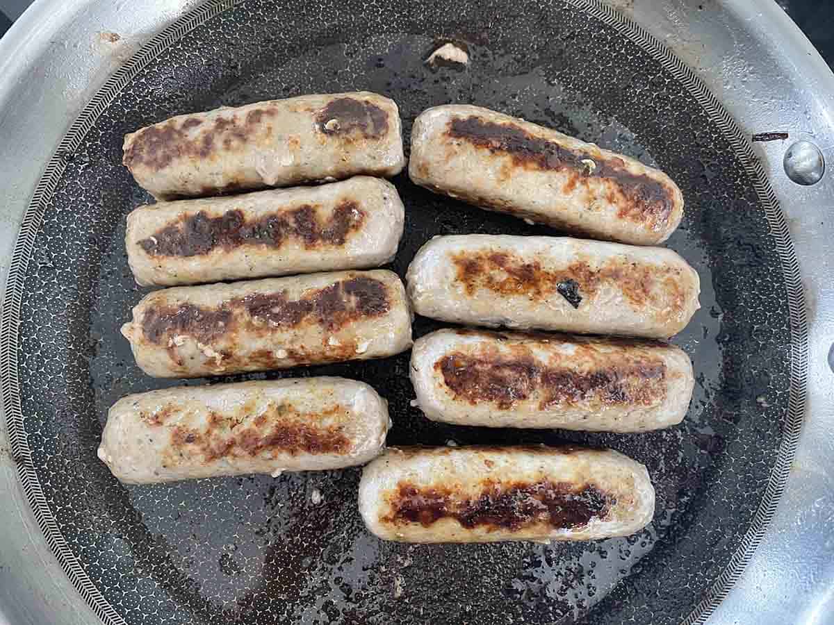 sausages frying in a pan.