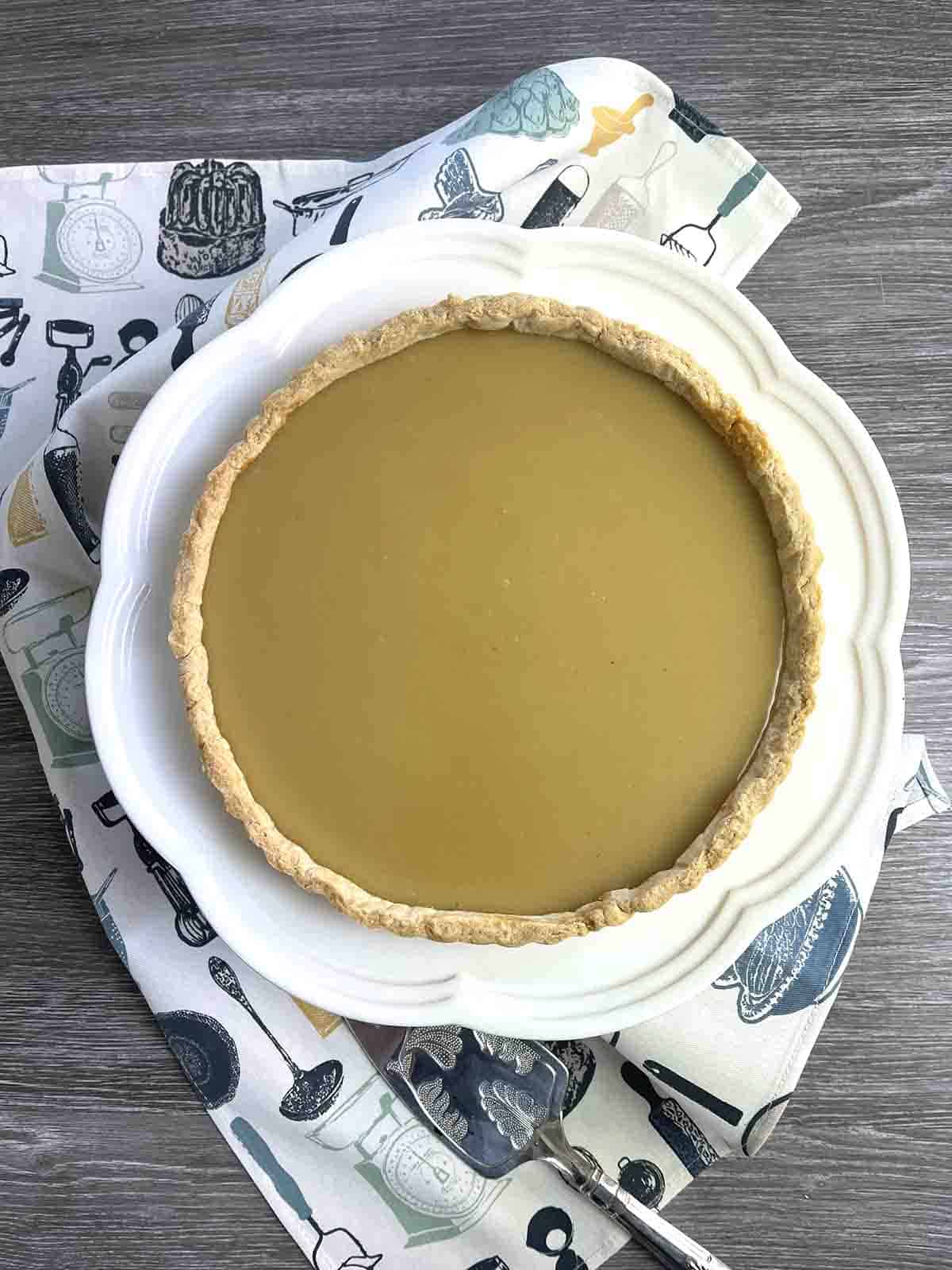 whole butterscotch tart on a white plate.