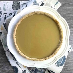 whole butterscotch tart on a white plate.
