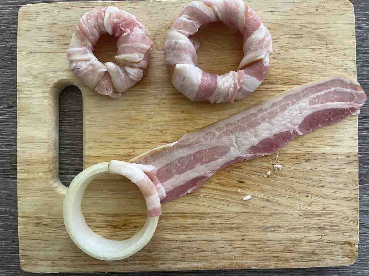bacon being wrapped around onion.