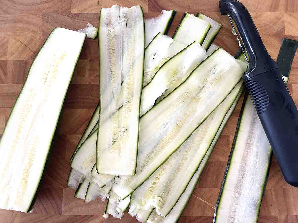 thin long slices of courgette on a board.