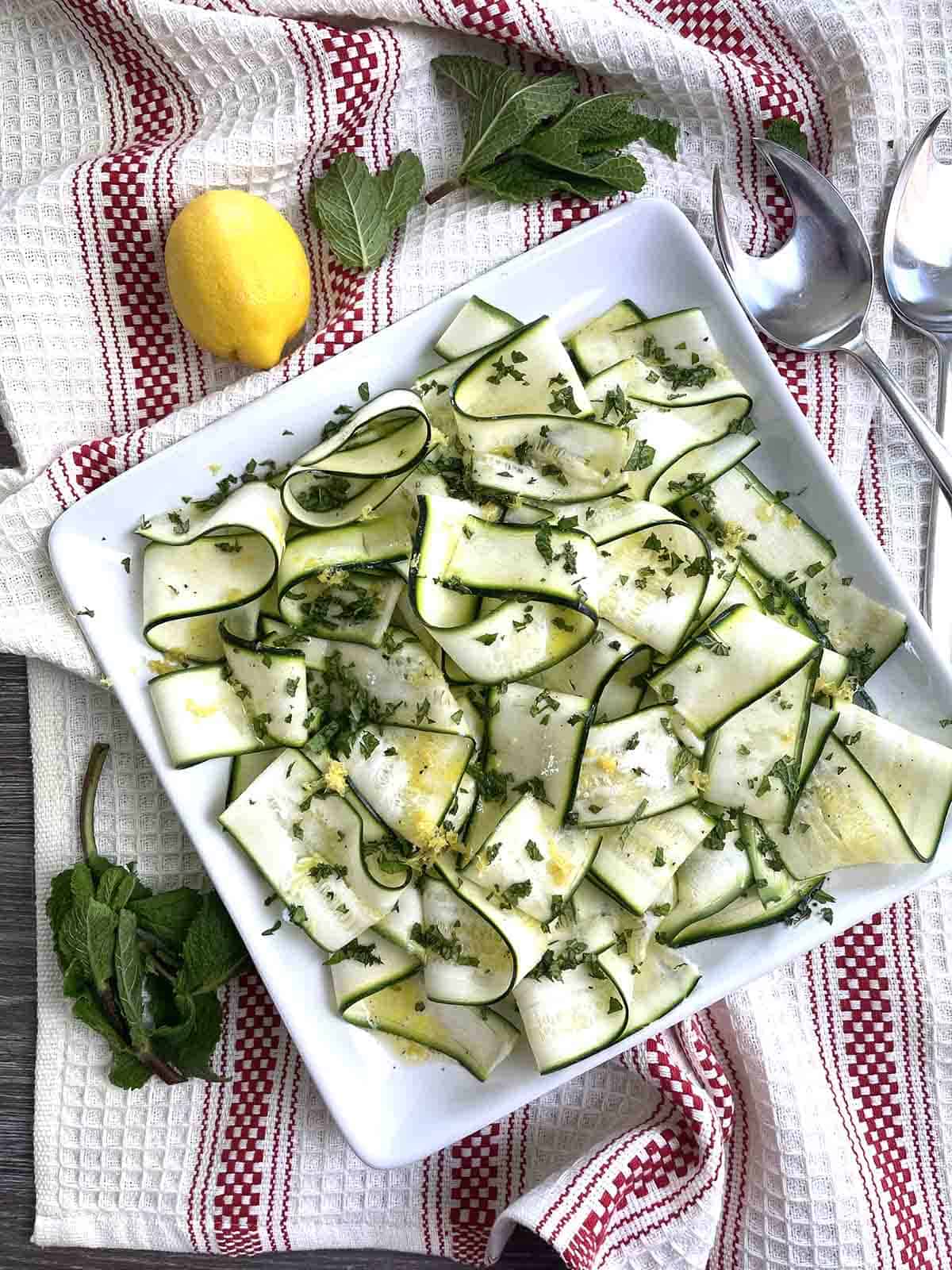 raw courgette salad on a square plate.