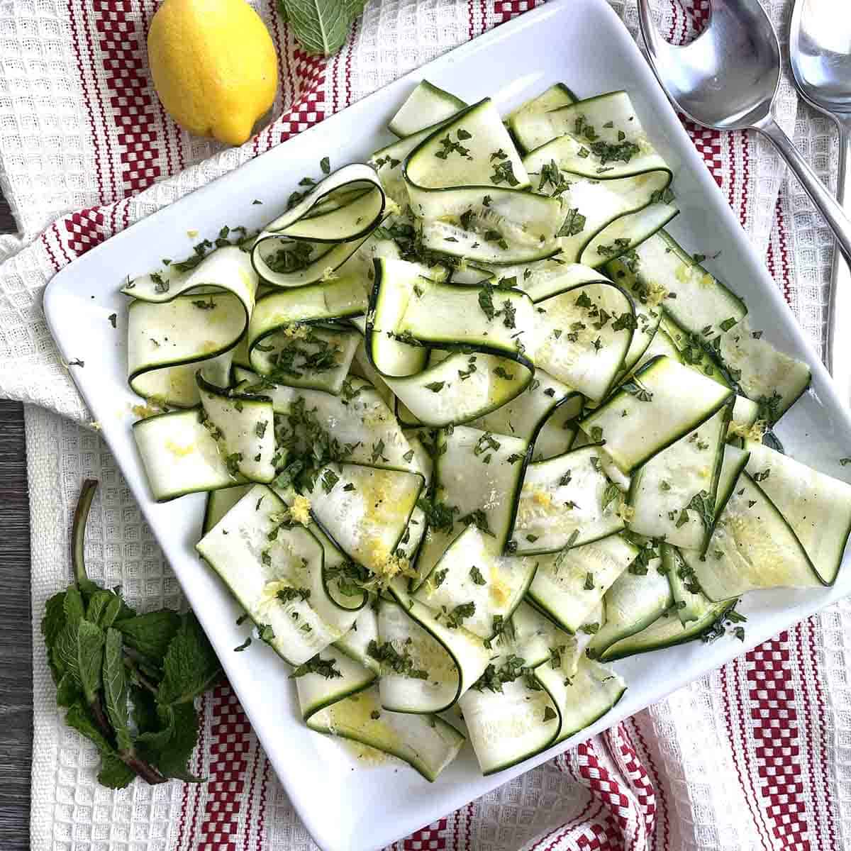 raw courgette salad on a square plate.