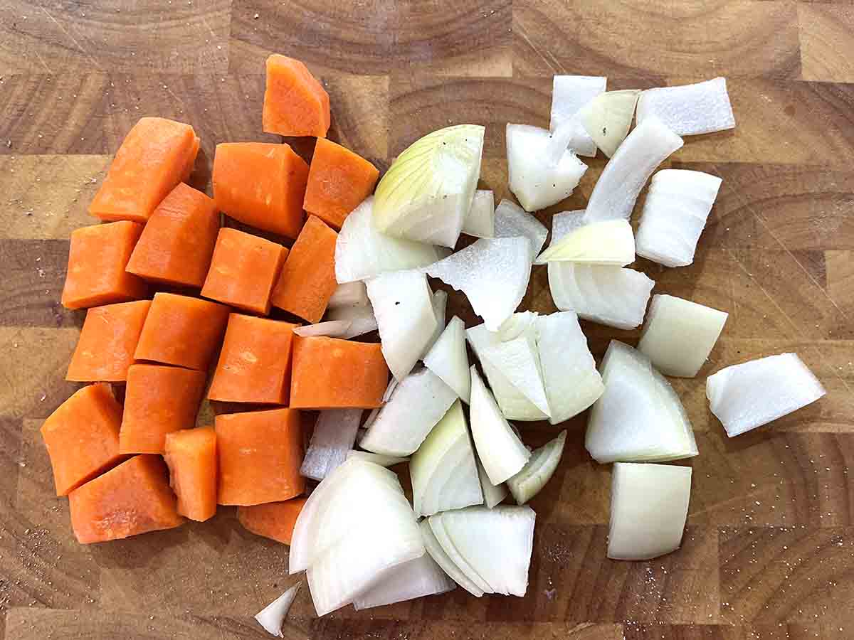 chopped carrots and onions on a board.