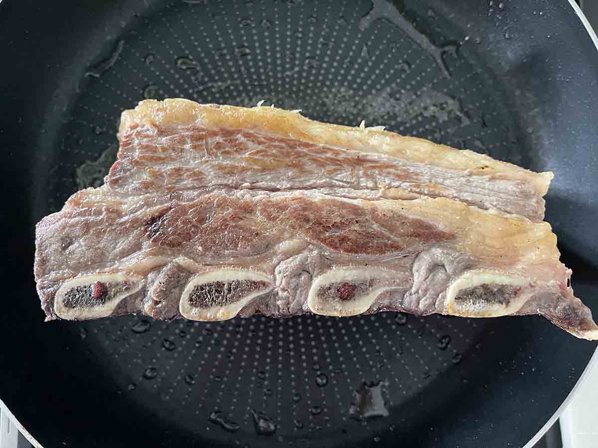 short ribs searing in a pan.