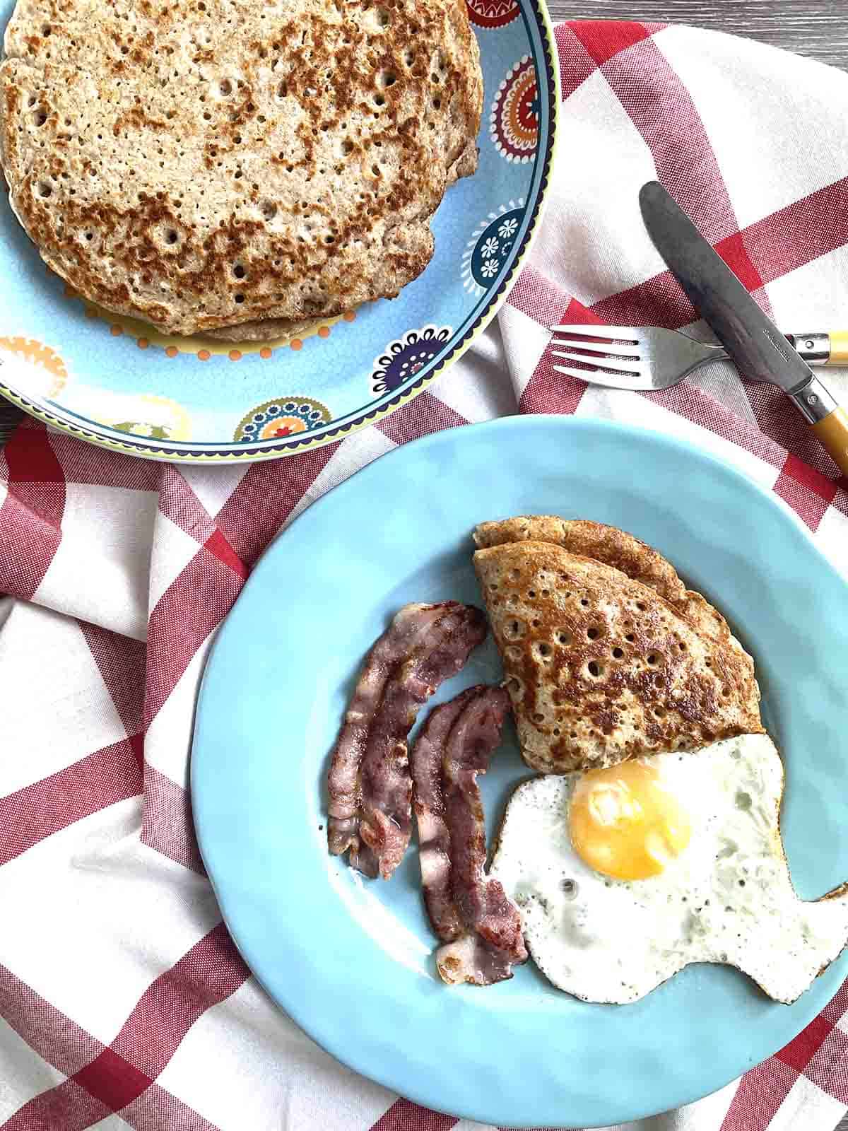 Derbyshire oatcake on a plate with egg and bacon.