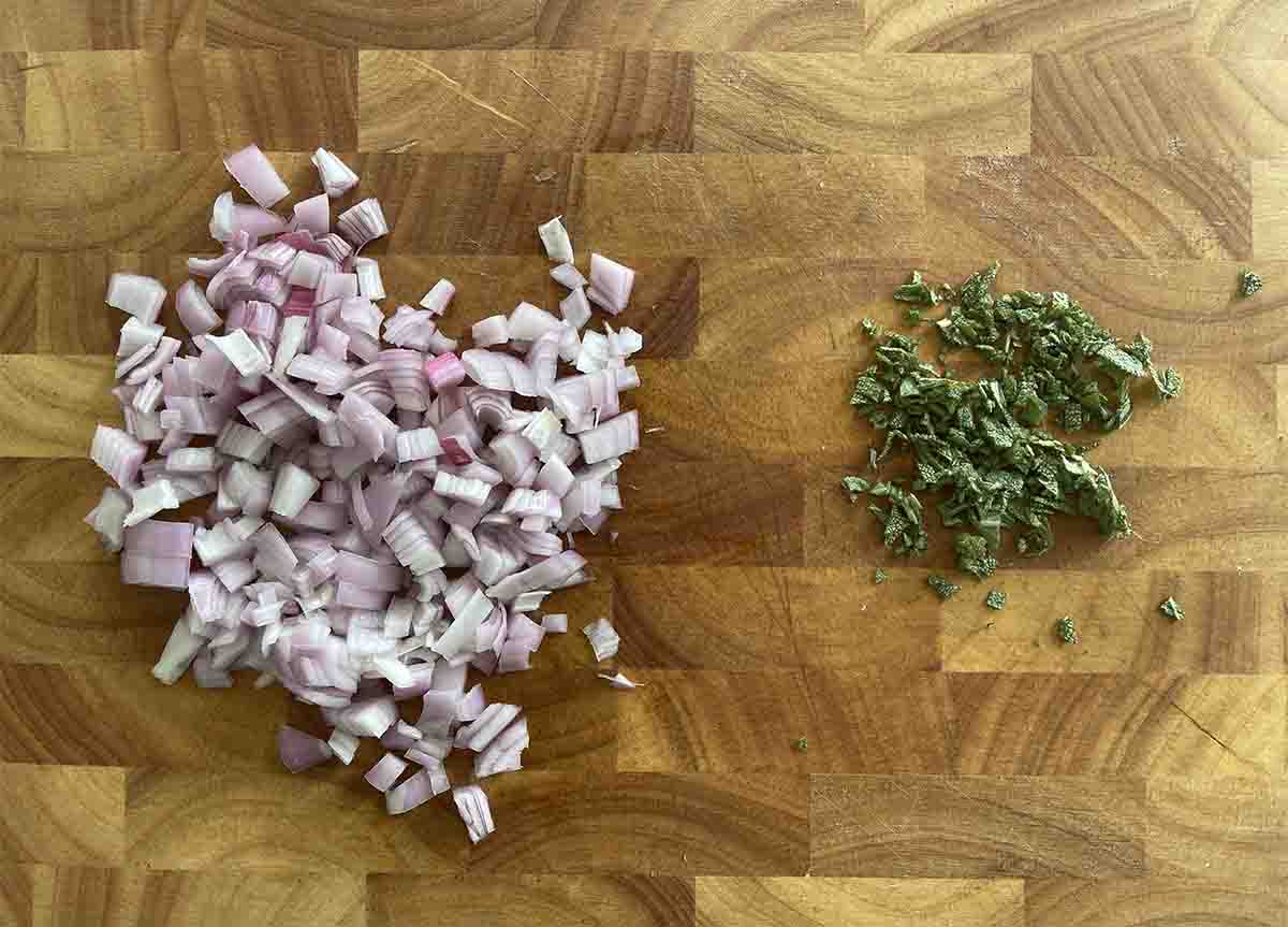 chopped sage and shallots on a board.