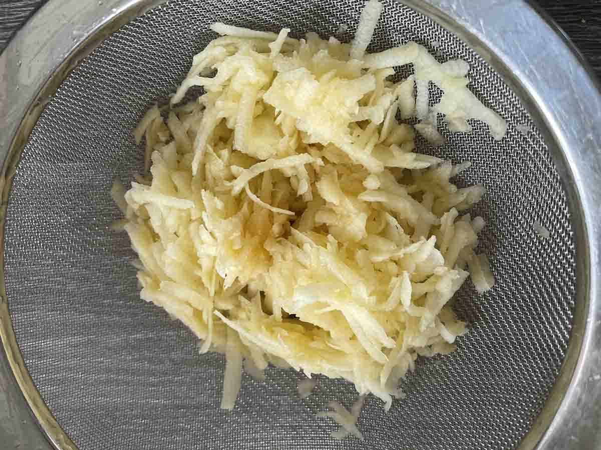 grated apple in a sieve.