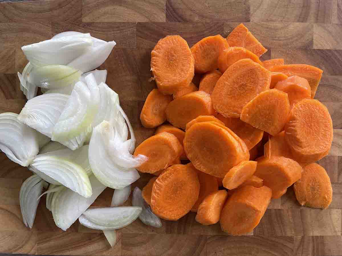 chopped onions and carrots on a board.