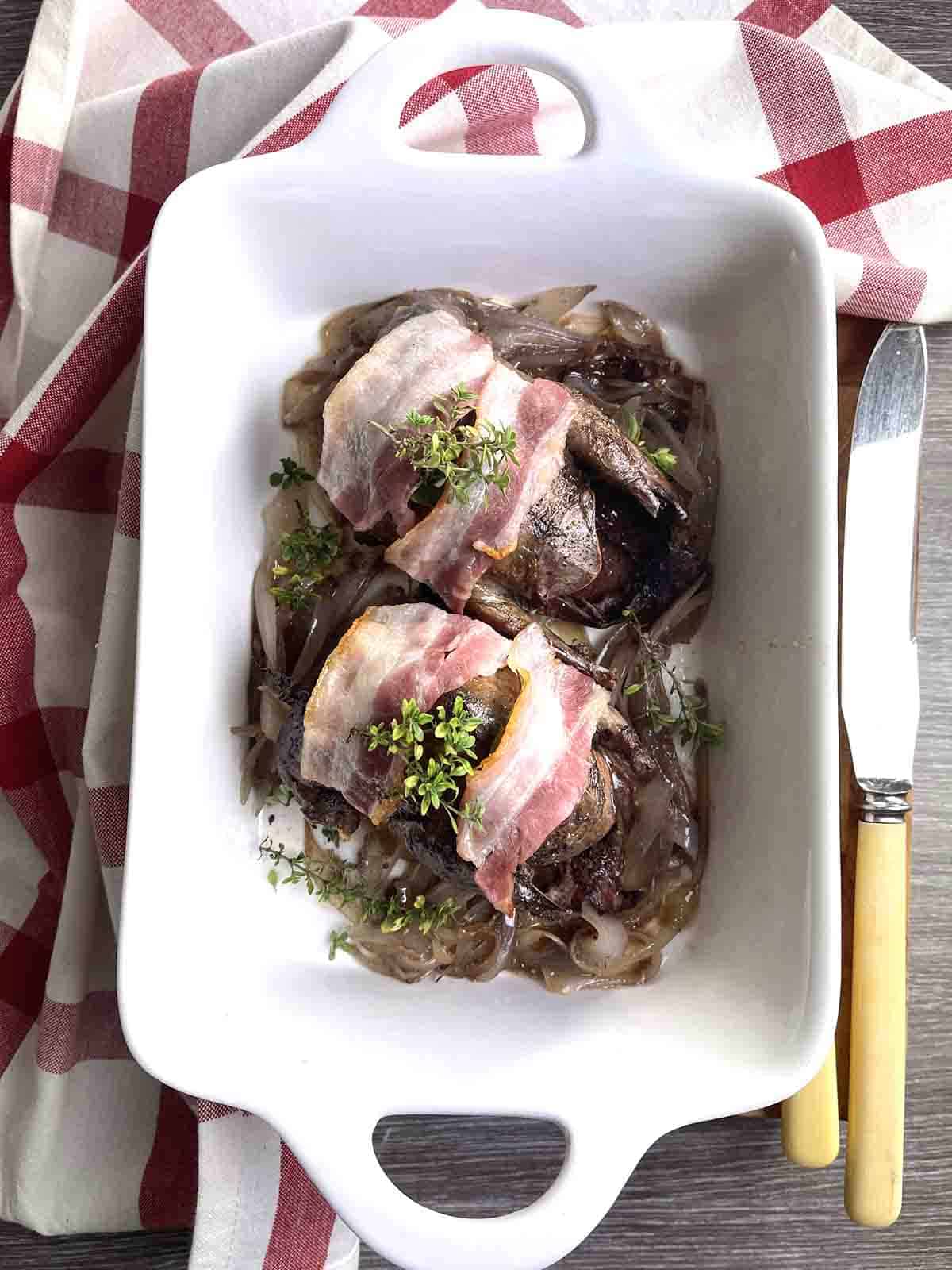 two roast pigeon in a dish.
